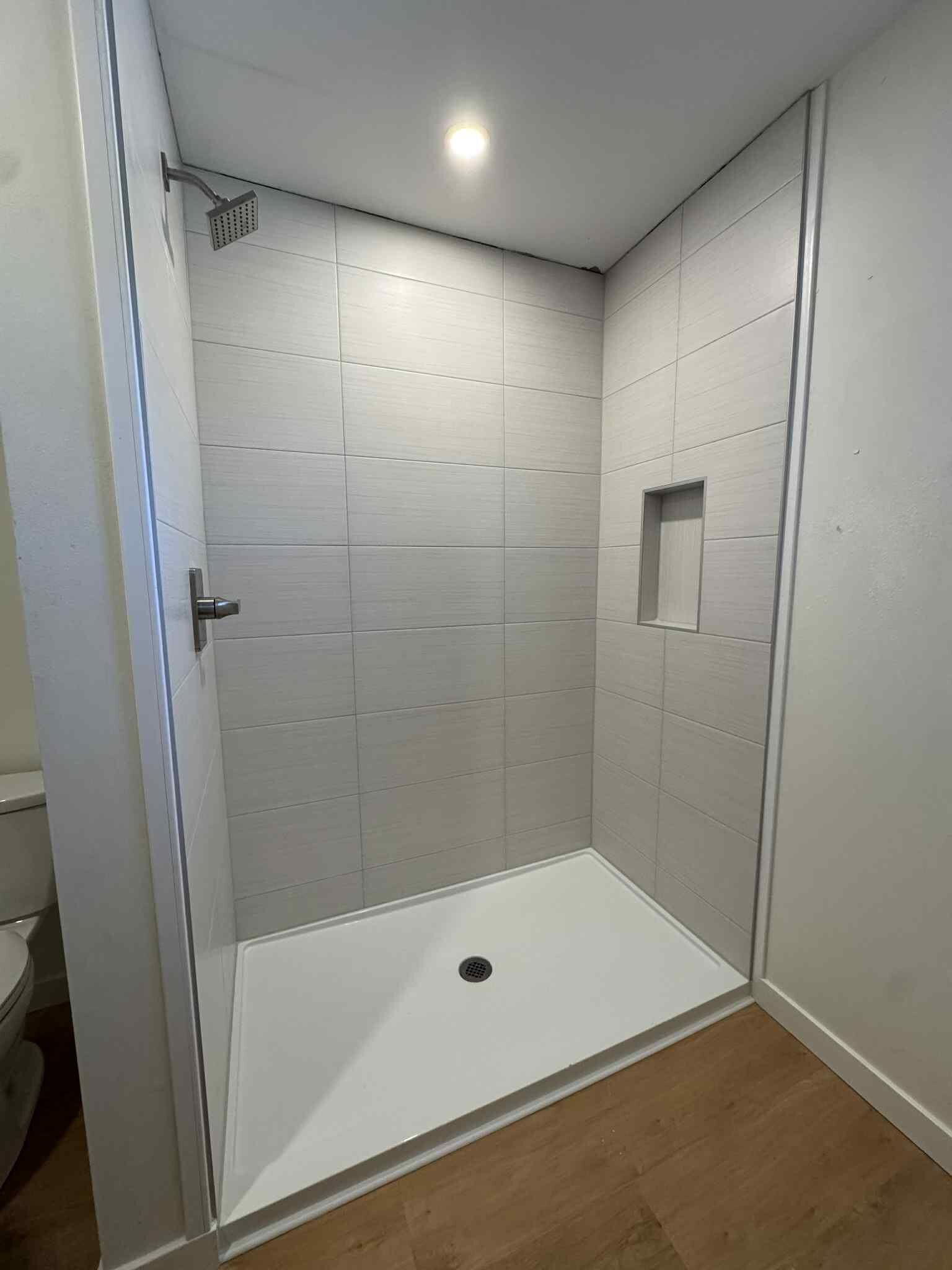 Marble-look tile shower with glass enclosure installed by MG Flooring