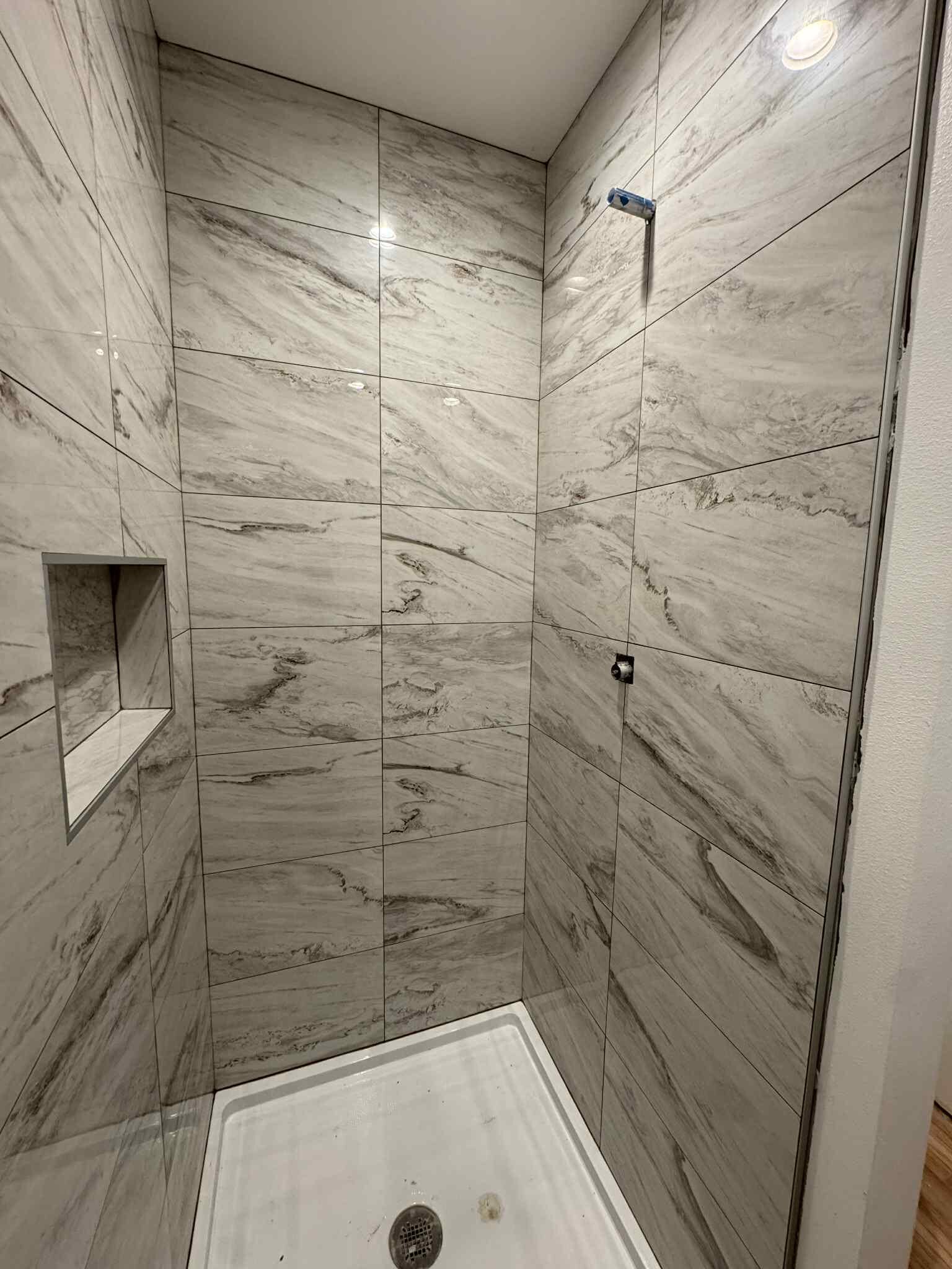 Marble-look tile shower with niche installed by MG Flooring